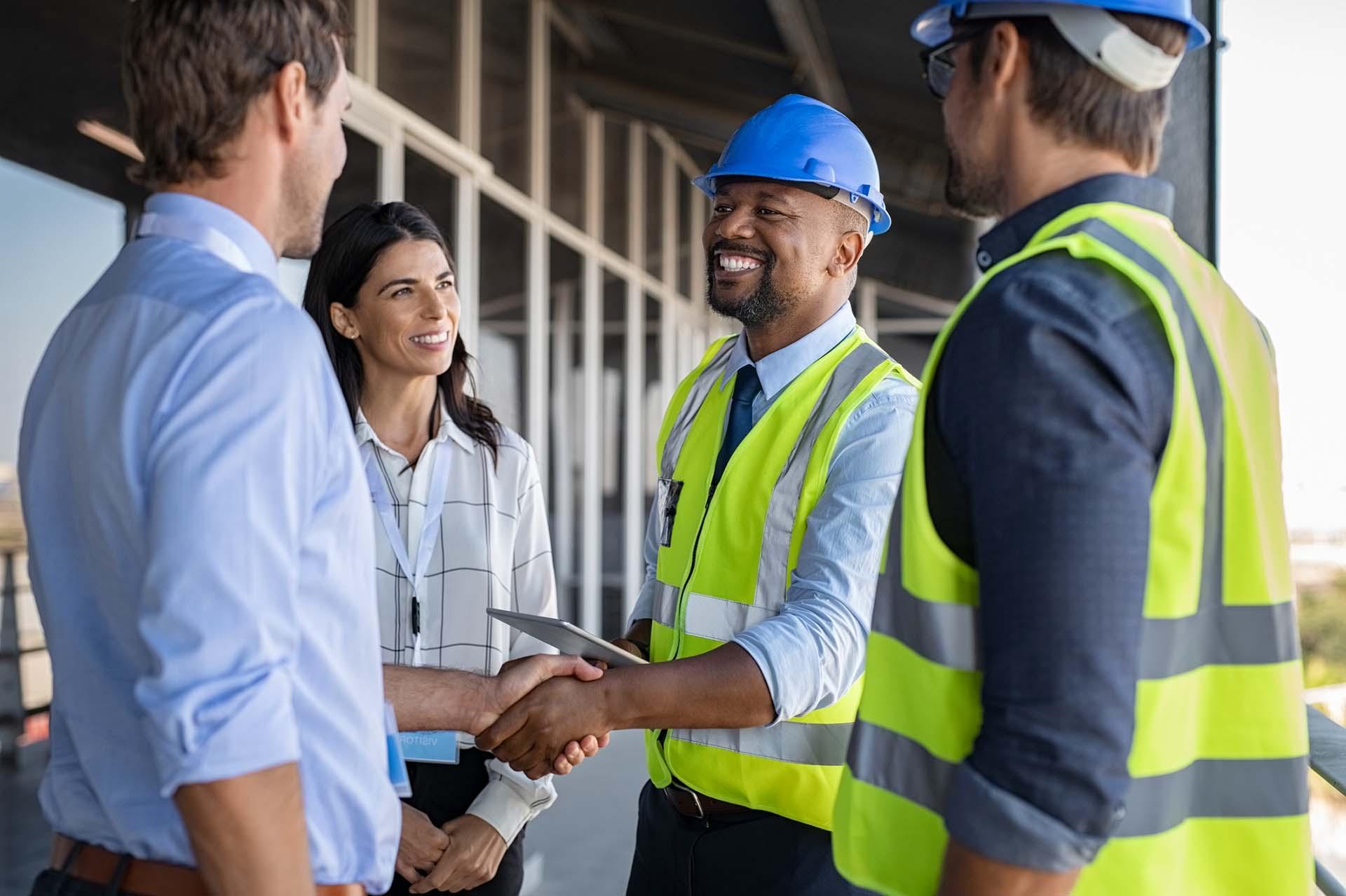 微笑的工程师在建筑工地与建筑师握手.
